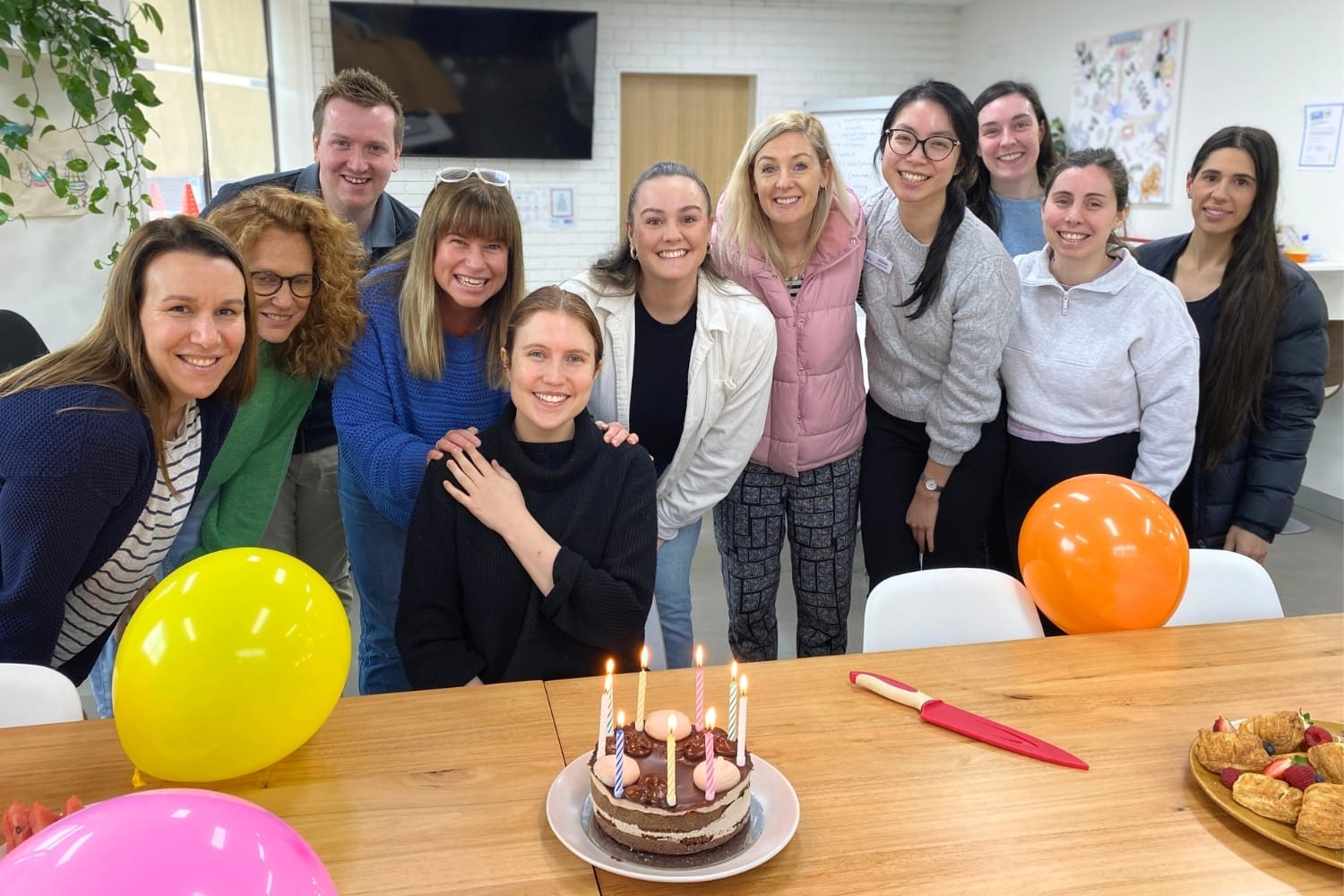Staff celebrating Maddie's birthday in the office with balloons and cake