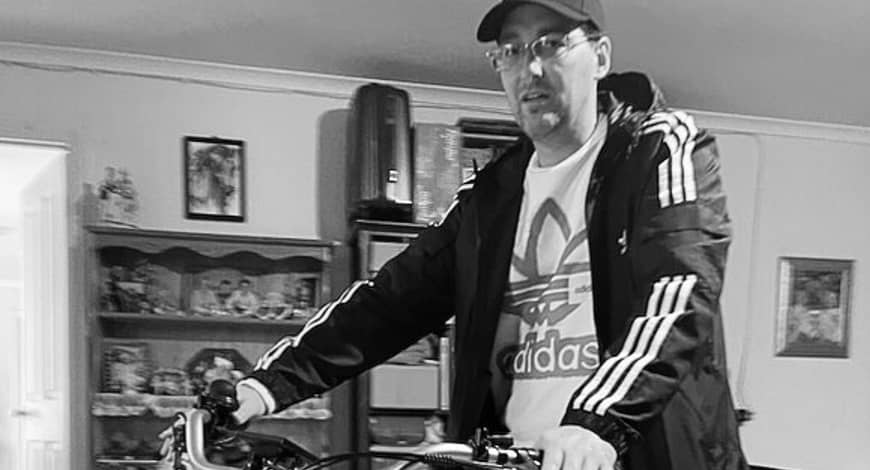 IRS client sitting on his new trike in his living room